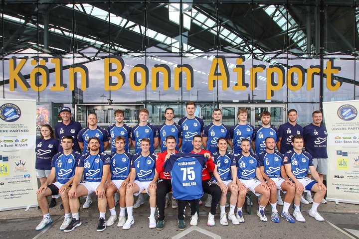 Handballmannschaft mit den vom Flughafen gesponserten Trikots vor dem Terminal 2.