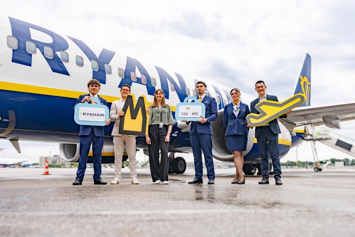 Mitarbeiter des Flughafens feiern den Erstflug mit der Ryanair Crew vor einem Flugzeug auf dem Vorfeld.